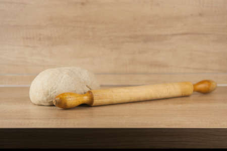 Dough for pizza and rolling-pin on wooden table