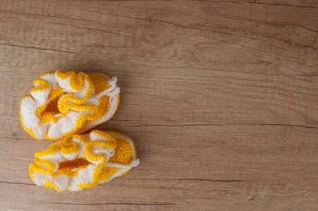 Handmade knitting baby shoes on wood tabletop.の写真素材