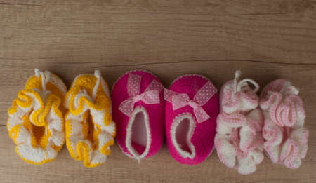 Handmade knitting baby shoes on wood tabletop.の写真素材
