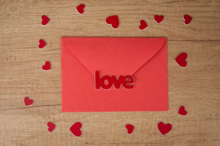 envelope with red paper hearts on wood background