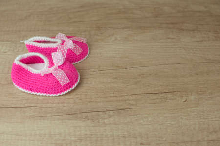 Handmade knitting baby shoes on wood tabletop.の写真素材