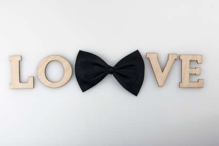black ribbon bow tie with wood letters LOVE on white background