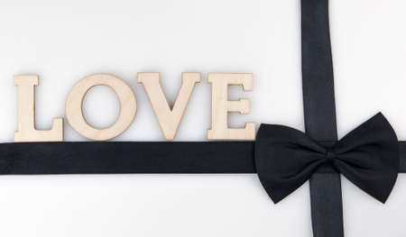 black ribbon bow tie with wood letters LOVE on white backgroundの写真素材
