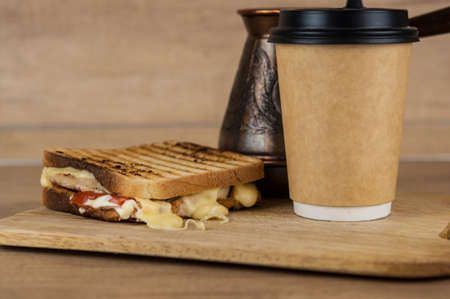 big sandwich with ham, cheese, tomatoes and disposable coffee cup on toasted bread