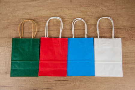 Colorful paper shopping bags on the floor against a wooden wall background. Sale, consumerism, advertisement and retail conceptの写真素材