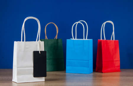 Colorful paper shopping bags on the floor against a blue wall background. Sale, consumerism, advertisement and retail conceptの写真素材