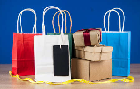 Colorful paper shopping bags on the floor against a blue wall background. Sale, consumerism,...