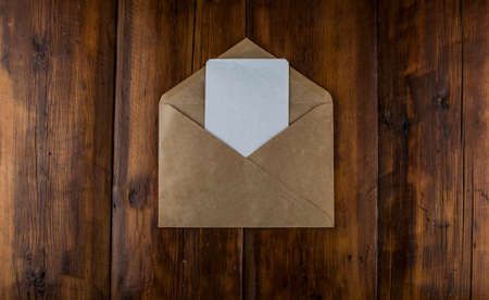 Top view of brown envelope and blank greeting card on wooden background.Copy space