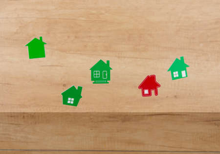 Flying in air miniature houses shapes on a wooden wall background. Real estate, insurance concept, mortgage, buy sell house, realtor conceptの写真素材