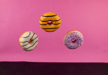 Donuts flying in the air on a pink background. Bakery, baking concept. Levitation. Copy space. Breakfastの写真素材