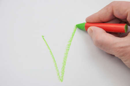 Female hand drawing tick on blank white paper. Cropped image of hand writing on checklistの写真素材