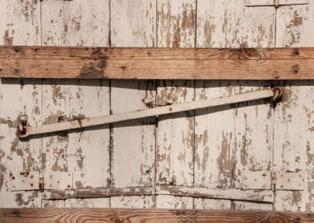 Colorful painted and weathered old wooden window shutters of abandoned huts locked with iron bar