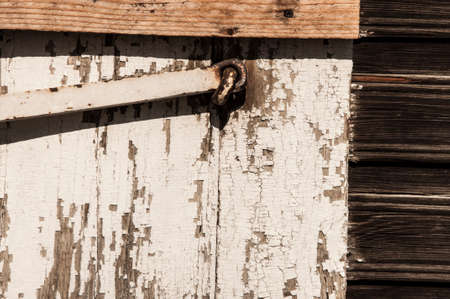 Colorful painted and weathered old wooden window shutters of abandoned huts locked with iron barの写真素材