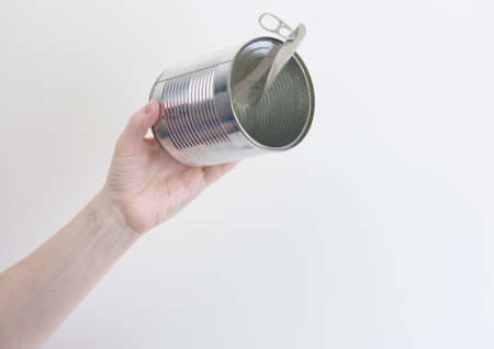 Female hand holding open empty tin can. Recyclable waste. Recycling, reuse, garbage disposal,...
