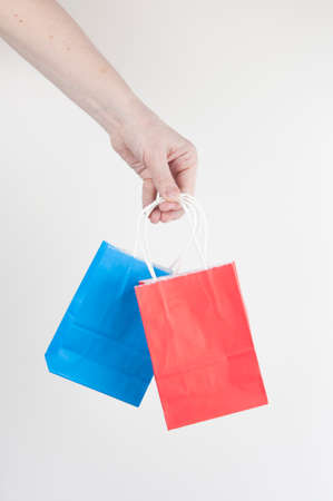 Woman's hand holding colorful shopping bags on white background. Close-up.の写真素材