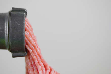 Steel meat grinder processing meat, cooking meat on white backgroundの写真素材