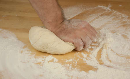 Baking concept. Unrecognizable man's hands top view knead dough on wooden table background. Male...