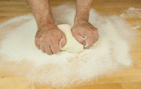 Baking concept. Unrecognizable man's hands top view knead dough on wooden table background. Male bakerの写真素材