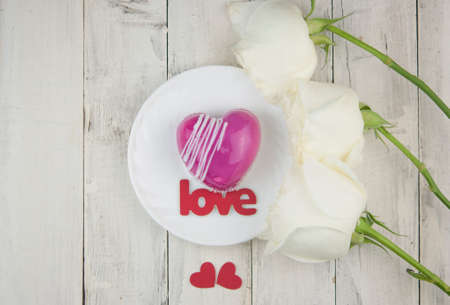 word love and white petals rose with red cake in the shape of a heart is on the table. Romantic date.の写真素材