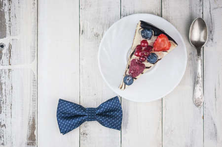 Mix berry slice cake on white plate with bow tie on old wood background Happy Father's Day.の写真素材
