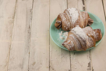Two fresh croissants in plate on white wooden table. Breakfastの写真素材