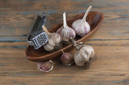 Organic garlic with metal press. Fresh garlic cloves and garlic bulb on a wooden table. Garlic for healthy eating. Concept of spices for healthy cooking. Top viewの写真素材