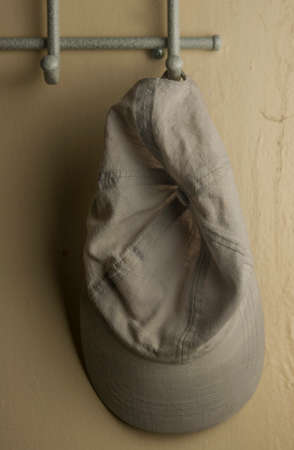 Empty hanger with gray metal and wooden elements on yellow textured wall and cap
