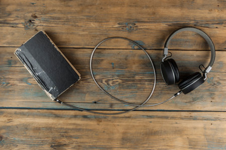 Audio book concept. Headphones and old book over wooden table. Top view with space for your text. Remote education concept.の写真素材