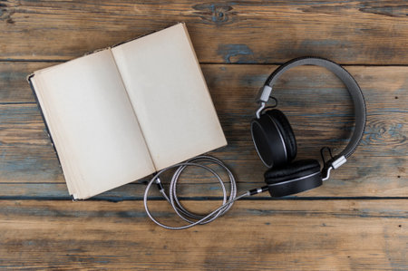 Open book with blank page and headphones on a wooden table. Remote education concept. Top viewの写真素材