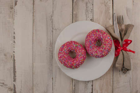 Donut on a plate and on a wooden table. Photo of sweets. Top view. Copy space. Mock-upの写真素材