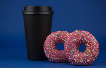 colorful donuts and disposable cup of coffee on a dark blue background. Photo of sweets. Copy space. Mock-upの写真素材