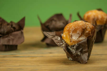 Homemade chocolate and vanilla cupcakes on a wooden table, sprinkled with powdered sugar