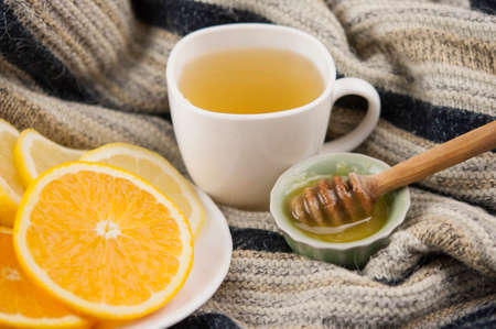 cozy autumn Breakfast with tea in white cup with honey and a warm knitted sweaterの写真素材