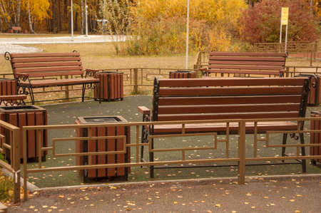 Autumn landscape, autumn in the city park. City park bench in the fall park, yellow fallen leaves on...
