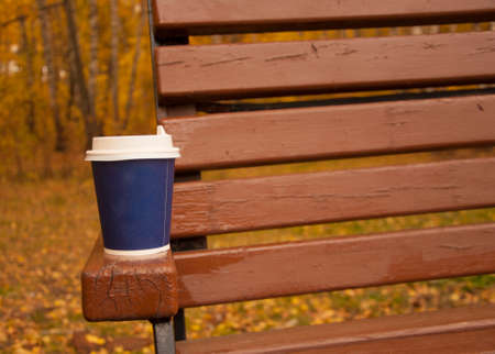 Coffee stands on a bench on the street. Cool weather. Warm up with aromatic coffee.の写真素材