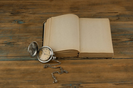Open vintage book with blank sheets and a watch on wood tableの写真素材