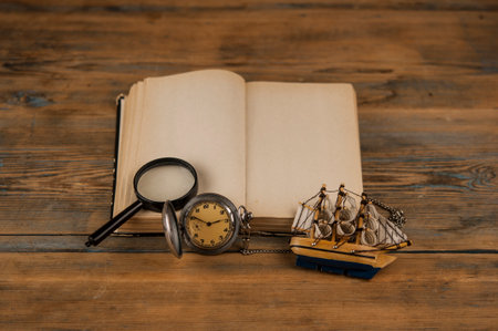 Open vintage book with blank sheets and a watch on wood tableの写真素材