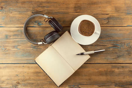 top view image of open book with blank pages next to cup of coffee on wooden table. ready for adding text or mockupの写真素材
