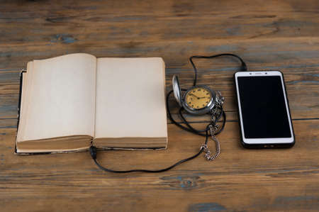 Black headphones with smarphone and open book are on the wooden table. Audio book concept. Distance learning. Close up, copy space, background.の写真素材