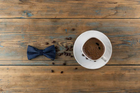 A cup of coffee on old wooden table with some roasted beans
