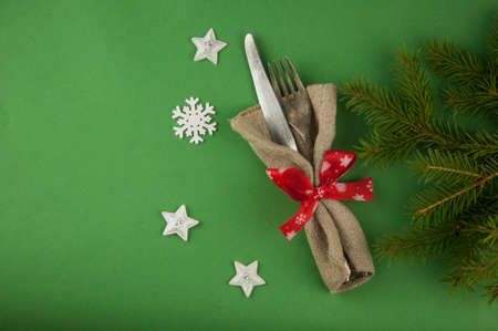Colorful rustic festive place setting with a knife and fork tied in a vivid festive Christmas napkin with string resting on a wooden table with copyspaceの写真素材