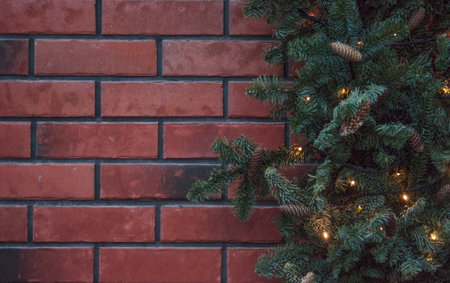 a christmas holiday red brick wall and green garland and hanging ball ornaments backdrop backgroundの写真素材