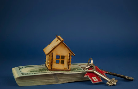 The concept of mortgage, sale and rental of housing and real estate. Buying a home. House-shaped and dollar bills. Keys with a house-shaped keychain. copy spaceの写真素材