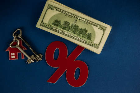 red percent sign and bills of banknotes on dark blue paper background. The concept of price changes on the real estate marketの写真素材