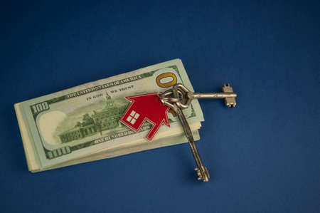The concept of mortgage, sale and rental of housing and real estate. Buying a home. House-shaped and dollar bills. Keys with a house-shaped keychain. copy spaceの写真素材