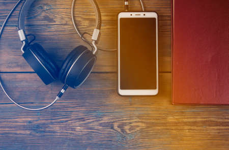 Audiobooks book and headphones black on wood table . top view. toned. Concept of listening to audio-books.の写真素材