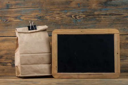 school lunch bag with blank blackboard on wood background