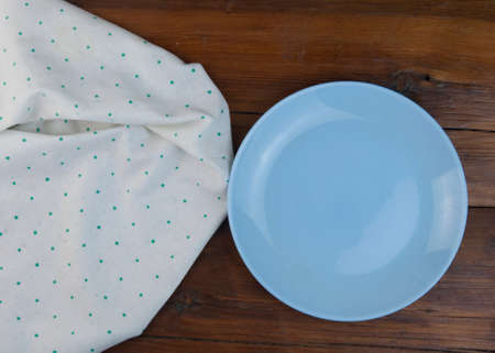 polka dot tablecloth or towel over the surface of a brown wooden table and blank plateの写真素材