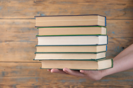 Child holding a high pile of thick black books in his hands