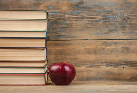 stack of books with red apple on the wood table with copy space. back to school